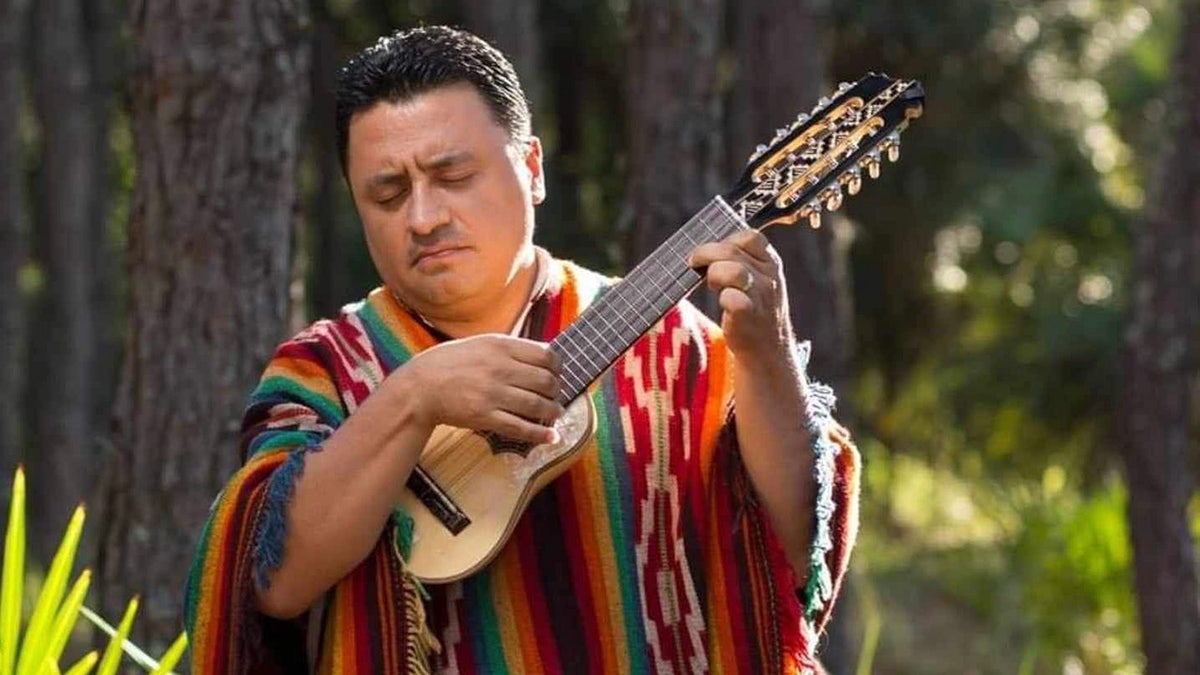 a man in a poncho playing a small guitar