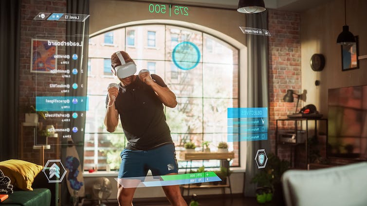 Man standing and using virtual reality headset and handheld controls in living room.